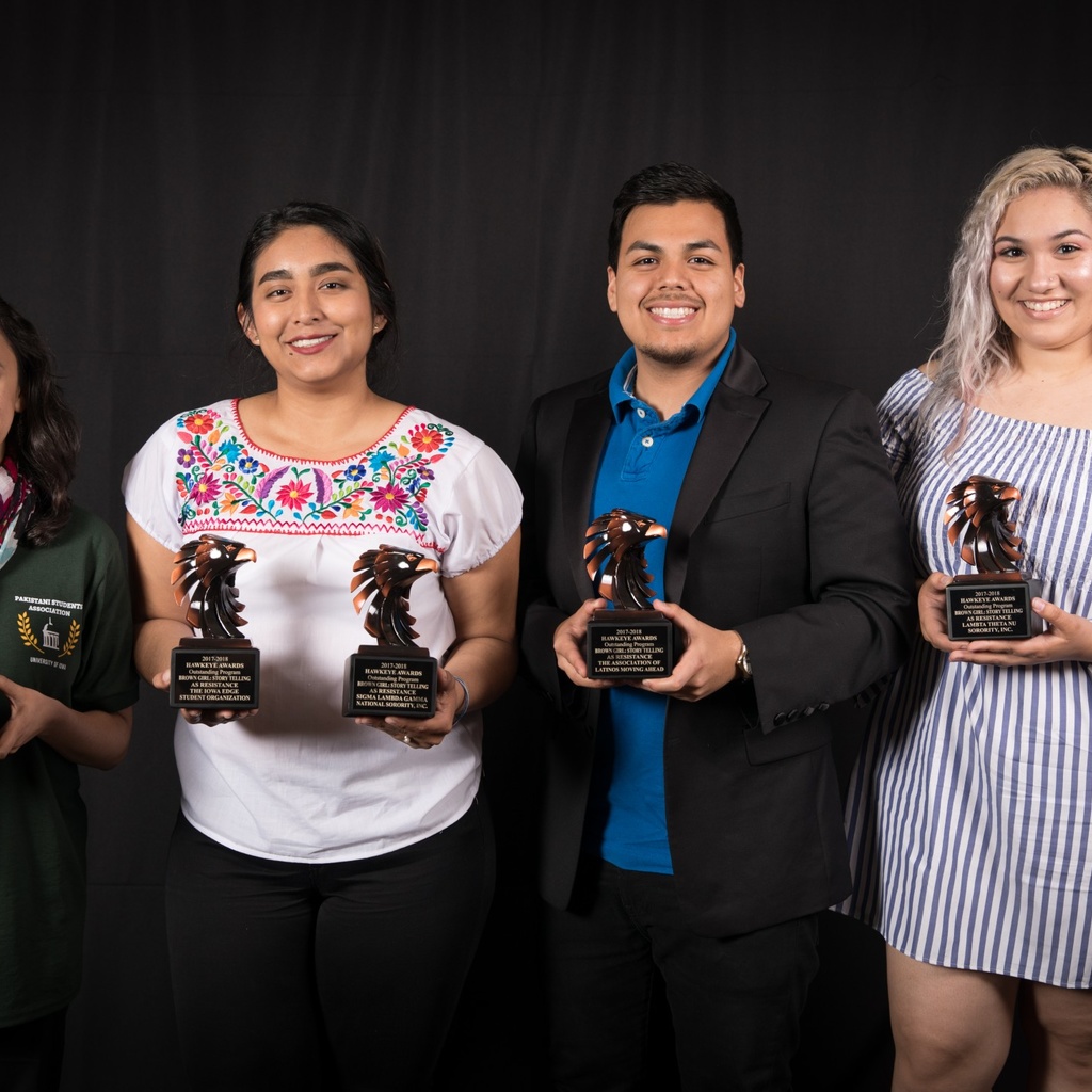 four students holding hawkeye service awards